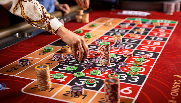 มือวางชิปบนโต๊ะรูเล็ตสีแดง
